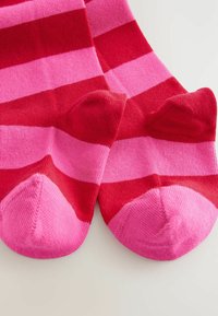 Stripede sokker i rød og pink, med brede vandrette farvebånd, blød striktekstur og forstærket tå-design.