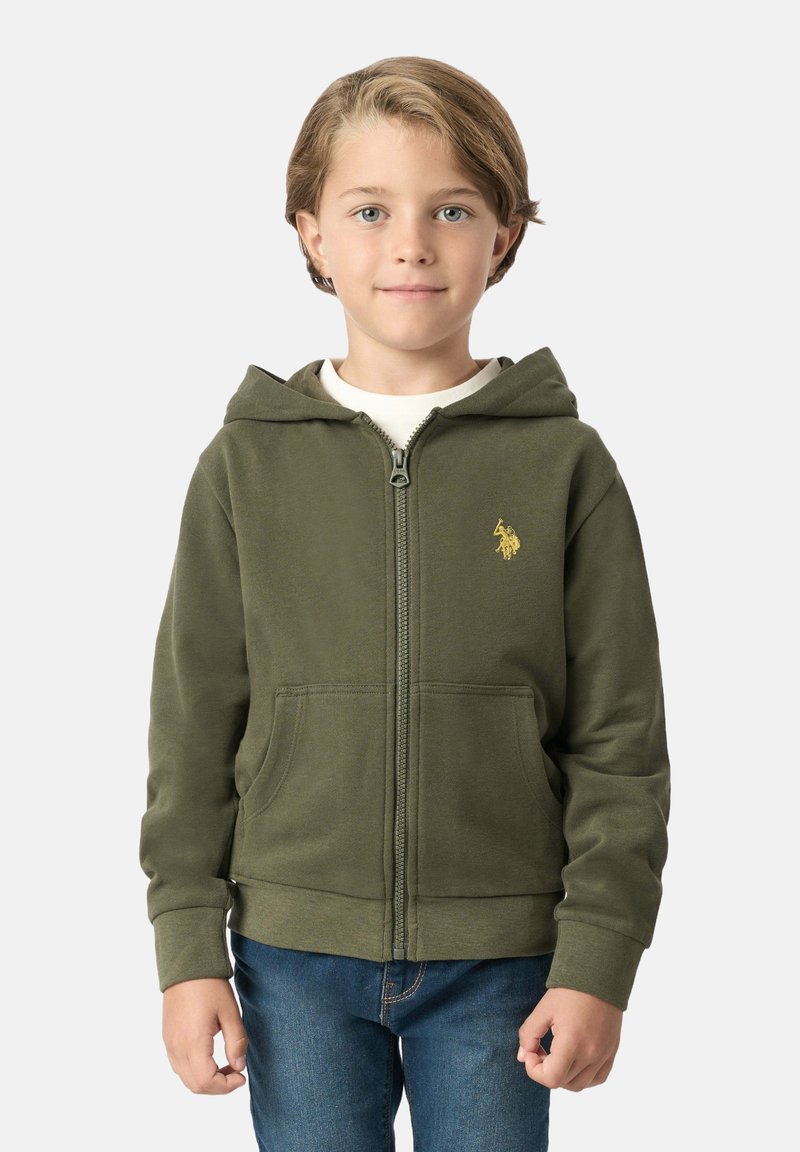 Felpa verde oliva con zip realizzata in un tessuto morbido, caratterizzata da una tasca a marsupio e un piccolo logo dorato sul petto. Il bambino la indossa sopra una maglietta bianca.