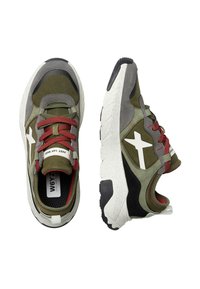 Une paire de baskets vertes et grises avec des semelles blanches, des lacets rouges, un logo en étoile sur les côtés, et le texte "JUST SAY WIZZ" sur la languette.