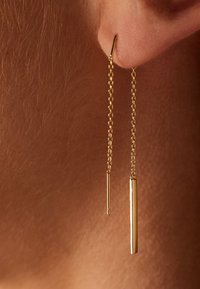 Gouden oorbellen met een dunne ketting met een lange staaf en een kortere stang die aan een eenvoudige haak hangen. Glad, glanzende afwerking en verfijnd design.
