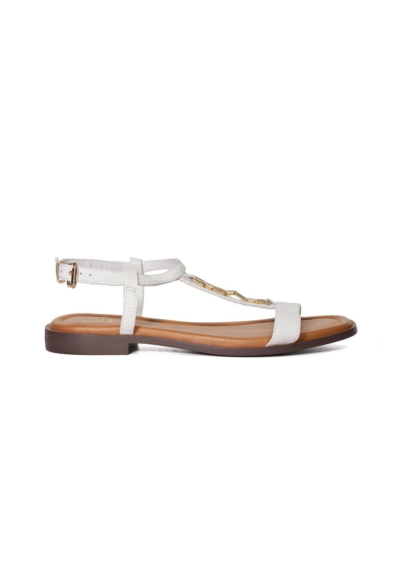 Witte platte sandalen met een T-bar ontwerp, gestructureerde banden, gouden hardwareaccenten en een bruine zool. Verstelbare enkelband voor een betere pasvorm.