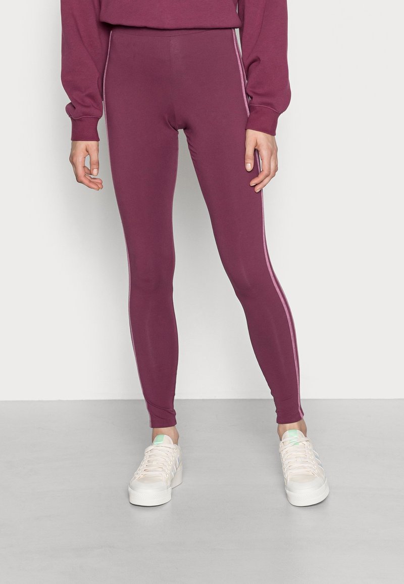 Deep burgundy leggings made of stretchy material, featuring a slim fit and contrasting light pink side stripes, with an elastic waistband.