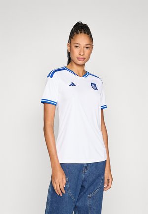 Camiseta de fútbol blanca con detalles y rayas azules, con cuello en pico y el escudo de la bandera griega en el pecho izquierdo.