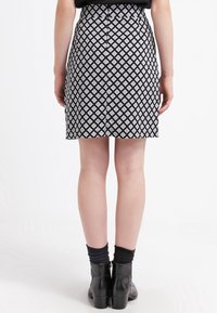 Mustavalkoinen kuviollinen hame, jossa on istuva malli, timanttikuvio, takana vetoketju ja suora helma.