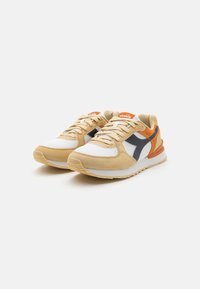 Beige and white sneakers with orange and navy accents. Made of mesh and suede, featuring a textured sole and flat laces.