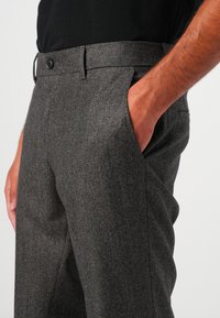 Pantaloni gri cu un model, cu croi drept, având închidere cu nasture, buzunare laterale și un material texturat.