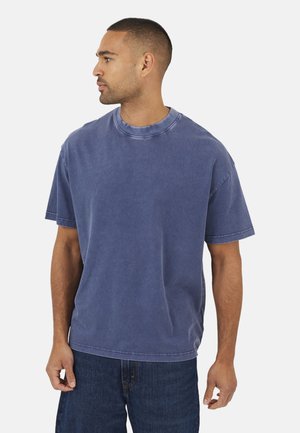 T-shirt en coton bleu avec un col rond, des manches courtes et une coupe décontractée. Présente des coutures visibles et une texture douce et usée.