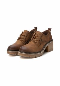 Zapatos de tacón de cuero marrón con diseño de cordones, punta redonda y suela gruesa. Presentan un bordado decorativo y un pequeño detalle de logo.