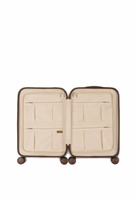 Beige kofferinterieur met meerdere met rits gesloten vakken en compartimenten. Heeft een bruine buitenrand en vier multidirectionele wielen voor mobiliteit.