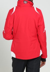 Rote wasserdichte Jacke mit weißen Akzenten, hohem Kragen und elastischen Bündchen. Verfügt über eine glatte Textur und ein sportliches Design.