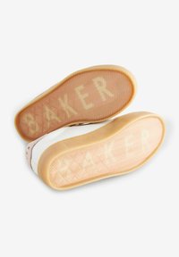 Soli delle sneaker con un motivo a spina di pesce, realizzati in un materiale gommoso trasparente. Testo "BAKER" visibile su ciascun suola in un colore chiaro.