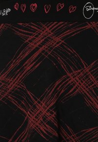 Schwarzer Stoff mit einem roten abstrakten Muster und sich kreuzenden Linien. Ein Bund zeigt rote Herzen und den Text "Gleich" in Weiß.
