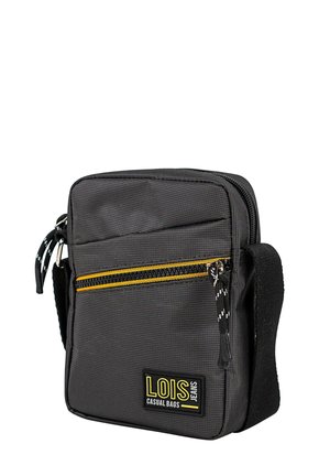 Bolso rectangular negro con superficie texturizada. Cuenta con un bolsillo amarillo con cremallera, correa de tela y una parche con el logo. Cierre superior con cremallera.