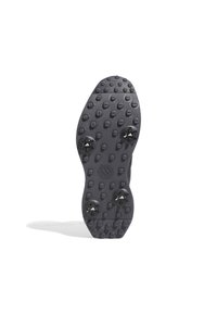 Black sports shoe sole with textured rubber, featuring protruding hexagonal patterns and three black cleats for traction.