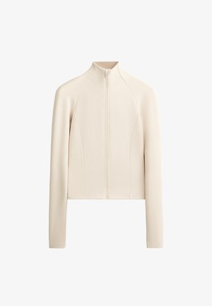 Giacca zip-up color beige chiaro con texture a coste, design aderente, collo alto e maniche lunghe. I dettagli delle cuciture esaltano l'aspetto strutturato.