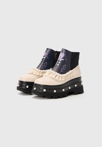 Chunky black-soled beige ankle boots with pearl studs, ruffled trim, and printed fabric featuring a vintage portrait on the front panel.