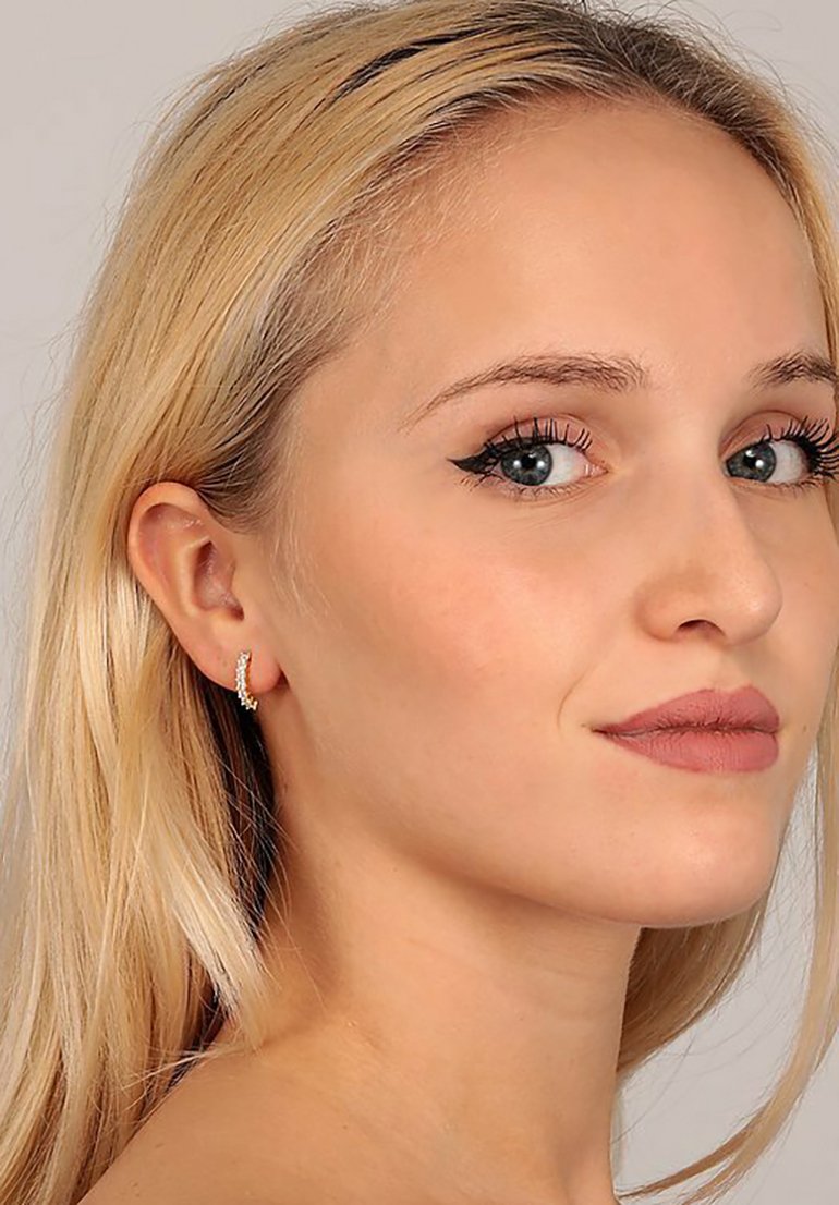Guldtonede hoops med små klare krystaller, der har et spiraldesign. Den strukturerede overflade forbedrer lysrefleksionen.