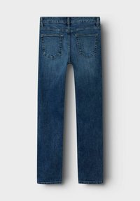 Sinised denim püksid, millel on sirge lõige, taga taskud, millel on kaarjas õmblus, ning veidi kulunud viimistlus. Ei ole nähtavat brändimist ega kaunistusi.
