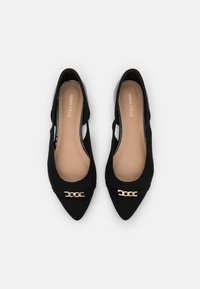 Svarta mocka ballerinas med spetsig tå, sidouttag och ett guld kedjeaccent över framsidan. Mjuk beige innersula.
