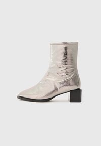 Bota de tobillo plateada metálica con puntera puntiaguda y tacón cuadrado. Textura suave, diseño elegante y detalle de costura minimalista.