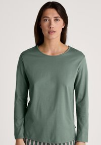Long-sleeve green top in soft cotton, featuring a round neck and relaxed fit. Texture appears smooth with minimal seams and no patterns.