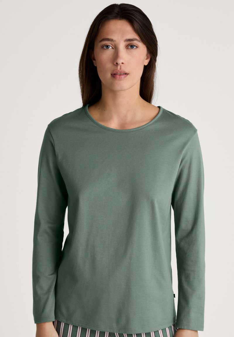 Long-sleeve green top in soft cotton, featuring a round neck and relaxed fit. Texture appears smooth with minimal seams and no patterns.