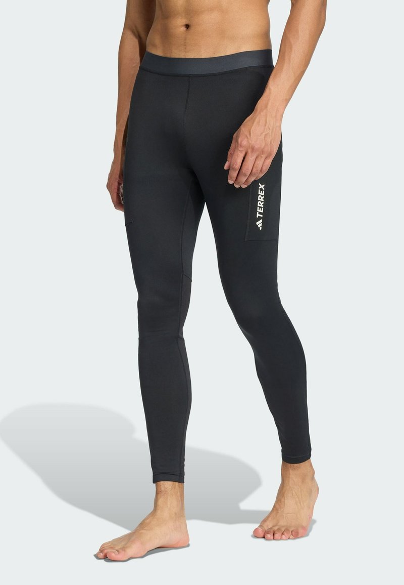 Čierne legíny priliehavého strihu vyrobené zo strečového materiálu, s širokým pásom a bočnou vreckom s bielym logom na stehne.