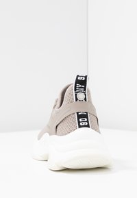 Baskets en maille beige avec une semelle blanche épaisse, une sangle grise au niveau du talon, et une languette noire à l'arrière avec le texte blanc "90".