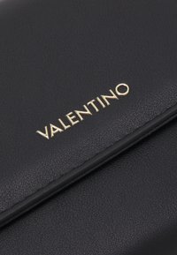 Czarny skórzany portfel o teksturowanej powierzchni z złotym logo "Valentino". Projekt ma elegancki, minimalistyczny styl.