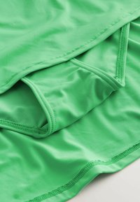Gröna idrottsshorts i ett slätt, stretchigt material, med rena fållar och en lagerdesign för ökad komfort.