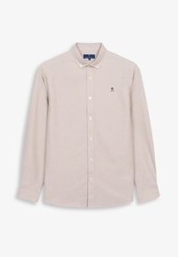 Camisa de manga larga color beige claro con cuello abotonado. Presenta un pequeño logo de calaveras en color navy en el lado izquierdo del pecho. Corte clásico y material de algodón.