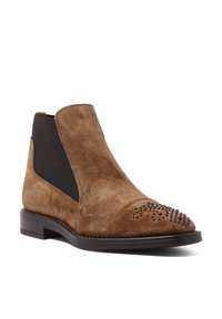 Botín de ante marrón con un panel lateral elástico negro, puntera redondeada y detalles decorativos de tachuelas en la puntera. Tacón de madera plano.