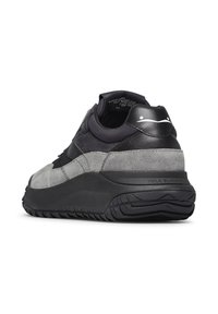 Sneaker in suede grigio e pelle nera con suola nera spessa, caratterizzata da una texture liscia, tallone rinforzato e branding minimale.