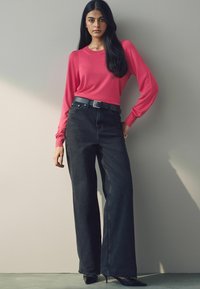 Fuksia pikkade varrukatega kampsun, millel on ribaga mansetid, koos kõrge talje ja mustade laia säärega teksadega ning musta vöödiga. Terava otstega kontsad lisavad ilmele elegantsi.
