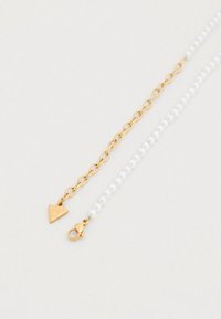 Χρυσό κολιέ αλυσίδας με λευκές πέρλες· διαθέτει τριγωνική ετικέτα με την εγχάραξη «Guess» και κλείσιμο με κούμπωμα καβουριού.