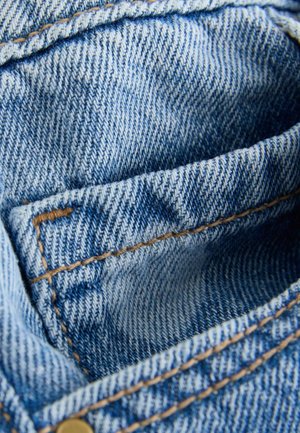 Jeanstyg med en ljusblå nyans, som kännetecknas av en tät väv och synliga sömmar i en kontrasterande beige färg. Inre fickor är framträdande.