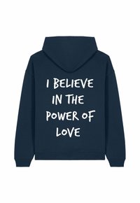 Sweat à capuche bleu marine avec un texte blanc audacieux au dos : "JE CROIS EN LA PUISSANCE DE L'AMOUR." Matière douce en mélange de coton.