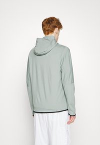 Hoodie in lichtgroen met een gestroomlijnd ontwerp, lange mouwen en een contrasterende zwarte zoom. Soepele textuur en een aangesloten silhouet.