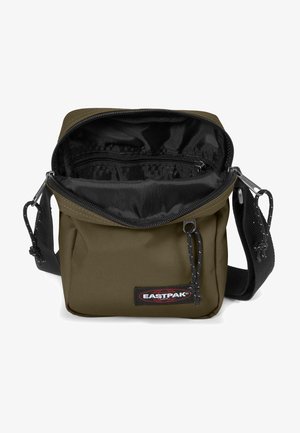 Borsa a tracolla in tessuto khaki con interno nero, scomparto con zip, tracolla regolabile e un grande etichetta con il logo Eastpak sul davanti.