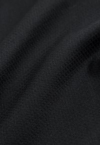 Tissu noir avec un motif tissé subtil montrant de doux plis et une texture en gros plan.