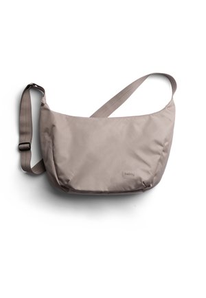 Sac en bandoulière taupe clair avec une texture lisse, forme rectangulaire, bandoulière ajustable et un détail de marque subtil. Large ouverture pour un accès facile.