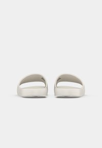 Lyse beige slip-on sandaler med åpen tå-design, glatt tekstur og minimalistisk stil. Begge sider har utskjæringer for ventilasjon.