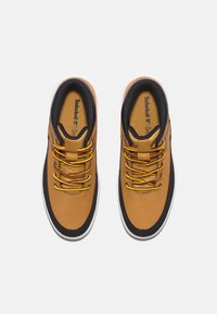 Scarpe in pelle marrone con accenti neri, lacci gialli e rossi, suola in gomma e collo imbottito. Dettagli di cucitura in contrasto visibili.