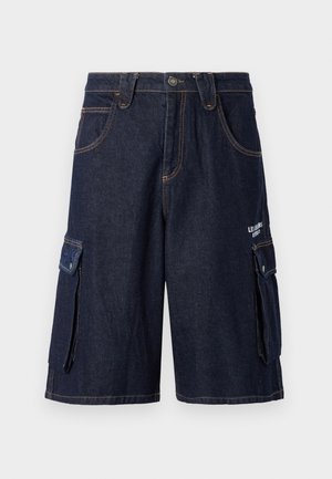 Pantaloni cargo in denim di colore blu scuro con cuciture arancioni a contrasto, cinque tasche e tasche cargo laterali. Presentano una chiusura con bottone.