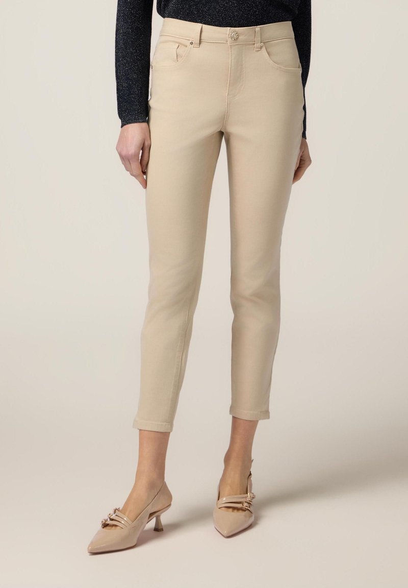 Beige katoenen broek in een slim fit met een vijf-pocket ontwerp en opgerolde manchetten, gecombineerd met lichtroze lakleren hakken.