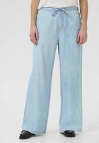 Pantaloni in denim a gamba larga di colore azzurro chiaro con vita regolabile tramite cordino, caratterizzati da una texture morbida e dettagli di cucitura discreti lungo le cuciture.