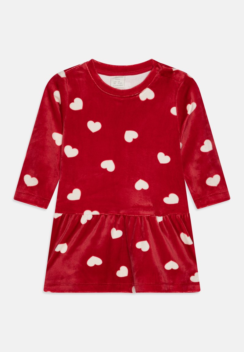 Robe en velours rouge avec des manches longues, motifs de cœurs blancs et jupe froncée. Elle comporte un col rond et une fermeture à bouton à l'épaule.