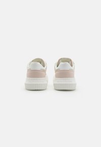 Adidași din piele albă și suede roz, cu o talpă din cauciuc texturat. Au un călcâi cu logo și un guler căptușit pentru confort.