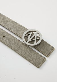 Cinto de couro texturizado cinza com uma fivela redonda de metal prateado com um design de letras entrelaçadas. O cinto possui vários buracos para ajuste.