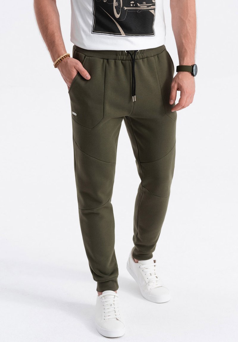 Olijfgroene joggingsbroek van zacht materiaal, met een kleurrijke tailleband, twee voorzakken en een taps toelopend ontwerp.